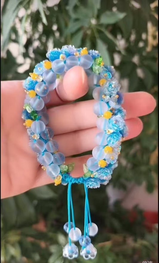 # hand - crafted with a cord, features light blue beads and colorful ornaments